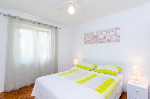 a white bedroom with a bed with yellow and green pillows at Studios Heliva in Dubrovnik