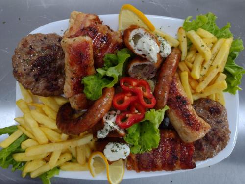 a plate of food with sausage french fries and lettuce at Zlatni San in Banja Koviljača
