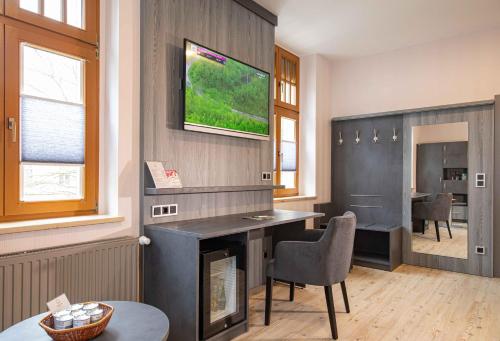 a living room with a fireplace and a tv on the wall at Parkhotel Plauen in Plauen