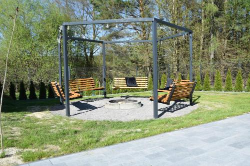 two benches and a fire pit in a park at Szklane Domy Roztocze 2 in Bondyrz
