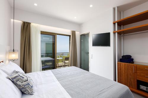 a bedroom with a white bed and a balcony at Elsa Exclusive Double Sea View - Adults Only in Plakias