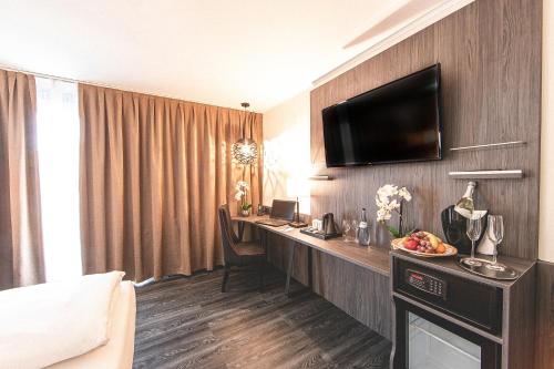 a hotel room with a desk and a television on a wall at PLAZA Residence Stuttgart-Ditzingen in Ditzingen