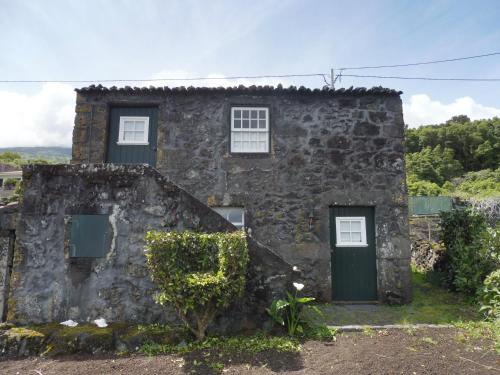 una antigua casa de piedra con una puerta verde en Casa da Adega en Prainha de Baixo