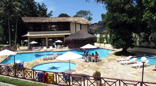 una piscina con sedie e ombrelloni di fronte a un edificio di MARESIAS - Frente p/ Praia - Cond. Fechado - Piscina Aquecida!!!Wi Fi Exclusiva a São Sebastião