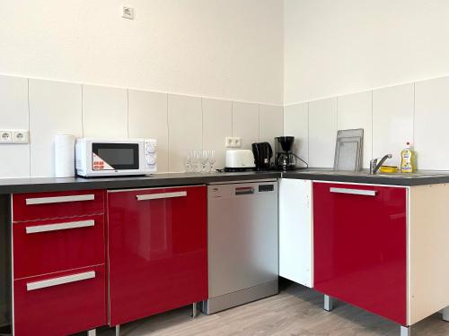 Kuchnia z czerwonymi szafkami i kuchenką mikrofalową w obiekcie Gerresheimer Republic w mieście Düsseldorf