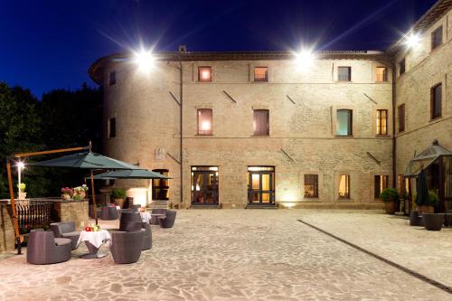 a large building with tables and umbrellas at night at Castello di Baccaresca in Branca