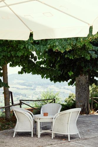 two white chairs and a table under an umbrella at Castello di Baccaresca in Branca
