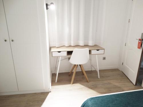 un escritorio en un dormitorio con una cortina blanca y una silla en Hotel Goya, en Crevillente