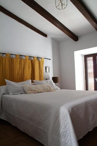 a bedroom with a white bed with a yellow curtain at El Barranquillo in Cazalla de la Sierra