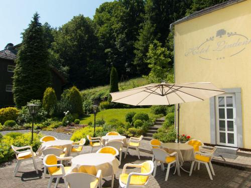 a restaurant with tables and chairs and an umbrella at Hotel Lindenhof in Monschau