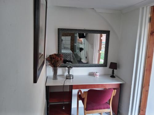 a mirror sitting on top of a desk with a chair at Dante Guest house in Alberton