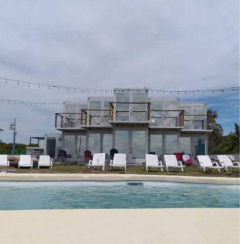 un edificio con sillas blancas y piscina en Nomada Republic Hotel Punta Chame, en Punta Chame