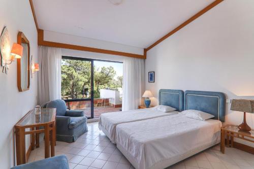 Un dormitorio con una cama y una silla y una ventana. en Apartment Dansk, en Quinta do Lago