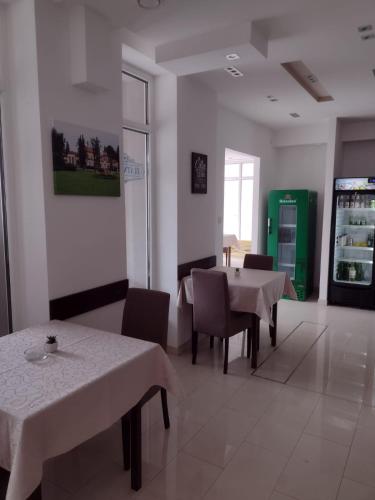 a dining room with tables and chairs and a refrigerator at Zlatni San in Banja Koviljača