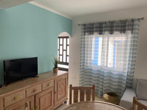 a living room with a television on a wooden dresser at Casa da Praia in Armação de Pêra