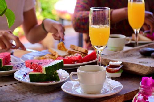 una mesa con platos de comida y vasos de zumo de naranja en Casa La Bella Samaria Boutique, en Santa Marta