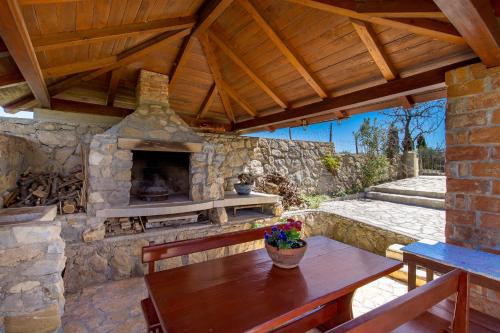 an outdoor patio with a stone fireplace with a wooden roof at Apartment Ursula in Lopar