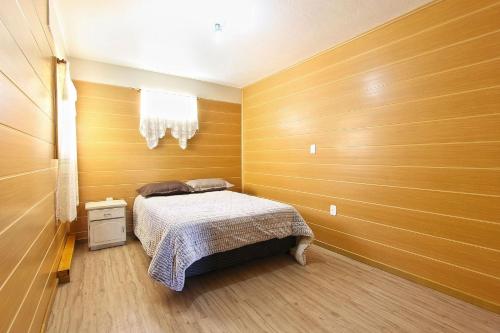 1 dormitorio con paredes de madera y 1 cama. en Dália 1 - My Home Temporada, en Gramado