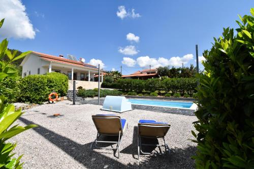 two chairs and a table next to a swimming pool at Quinta da Borboleta in Vila Nova de Poiares