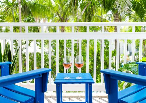 two wine glasses on a blue table next to a blue bench at Parrot Key Hotel & Villas in Key West