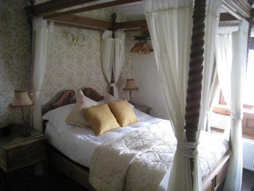 a bedroom with a canopy bed with curtains and a window at Rosebud Cottage Guest House in Haworth