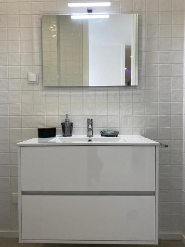 a bathroom with a white sink and a mirror at Ninho Citadino Aveiro in Aveiro