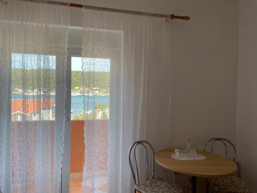a table and chairs in a room with a window at Guesthouse Tariba in Supetarska Draga