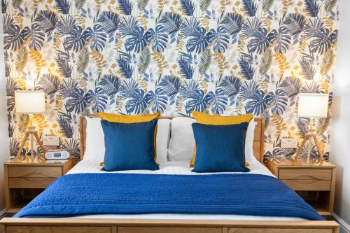 a bedroom with a blue bed with a tropical wallpaper at Stover Lodge in Torquay