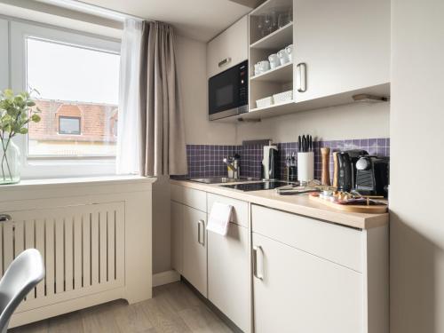 a kitchen with white cabinets and a window at limehome Berlin Chausseestraße in Berlin
