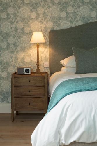 a bedroom with a bed and a nightstand with a clock on it at Farlam Hall Hotel & Restaurant in Brampton