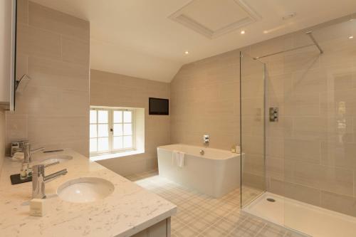 a bathroom with a tub and a sink and a shower at Farlam Hall Hotel & Restaurant in Brampton