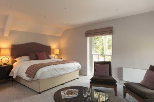 a bedroom with a bed and a chair and a table at Farlam Hall Hotel & Restaurant in Brampton