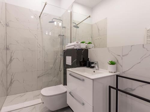 a white bathroom with a toilet and a shower at VacationClub – Wisus Apartament 19 in Świnoujście