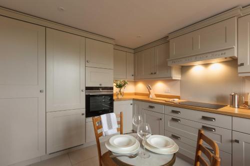 a kitchen with white cabinets and a table and chairs at Farlam Hall Hotel & Restaurant in Brampton
