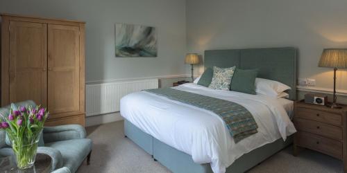 a bedroom with a large bed and a chair at Farlam Hall Hotel & Restaurant in Brampton