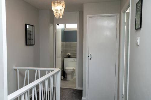 a hallway with a bathroom with a toilet and a chandelier at Large Modern Contractor House - FREE Parking - Staycations Welcome in Northfleet