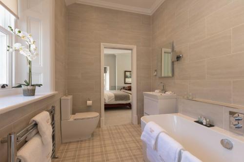 a bathroom with a tub and a toilet and a sink at Farlam Hall Hotel & Restaurant in Brampton