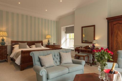 a bedroom with a bed and a couch and a table at Farlam Hall Hotel & Restaurant in Brampton