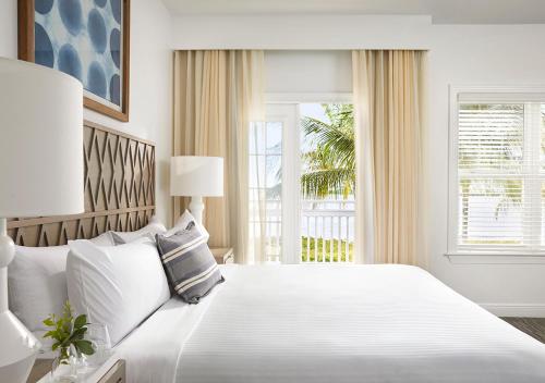 a white bedroom with a large bed and a window at Parrot Key Hotel & Villas in Key West