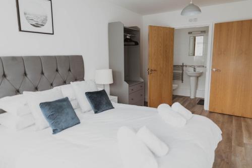 um quarto com uma cama branca e 2 almofadas azuis em Ocean 1- Sea View apartment, Fistral Beach Newquay em Newquay