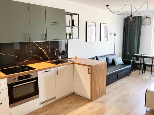 a kitchen and a living room with a couch at Apartament 47 Letnica in Gdańsk