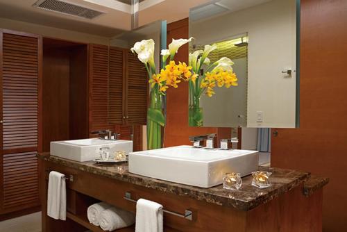 ein Badezimmer mit zwei Waschbecken und einer Vase aus Blumen in der Unterkunft Dreams Las Mareas All Inclusive in El Jobo
