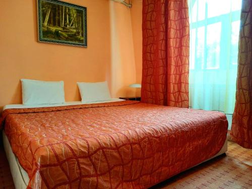 a bedroom with a bed with red sheets and a window at Family Art Hotel Gallery in Pleven