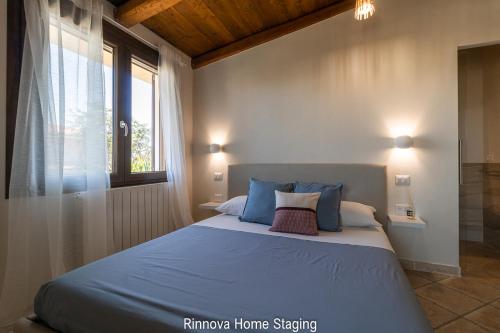 - une chambre avec un lit doté d'oreillers bleus et d'une fenêtre dans l'établissement La Botte e il Vino B&B, à Capoterra