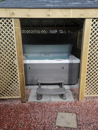 a hot tub in a wooden structure with a bench at Glenfern Guest House and a separate Cottage with its own private hot tub in Balloch