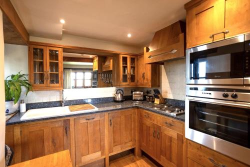 a kitchen with wooden cabinets and stainless steel appliances at Aslan in Chipping Norton