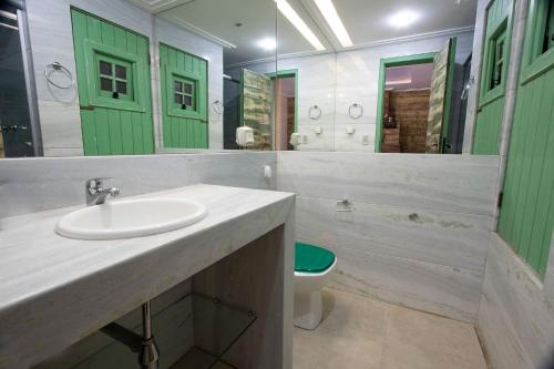 baño con lavabo, aseo y puertas verdes en Morada do Lago - My Home Temporada, en Gramado