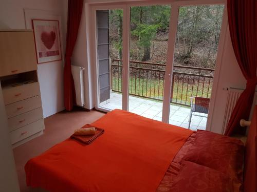 a bedroom with an orange bed and a large window at Hotel Rakitna in Rakitna
