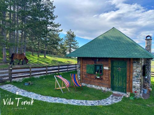 a small cabin with two chairs and a horse in a field at Vila Mali Tornik in Zlatibor