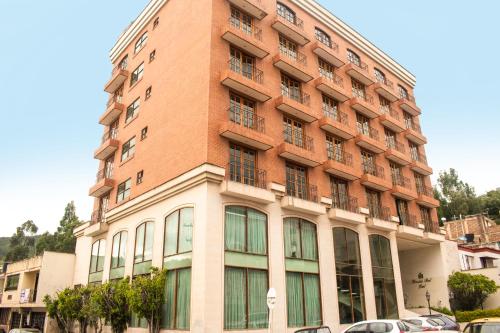 a tall red brick building with cars parked in front of it at Hotel Dinastia Real in Duitama
